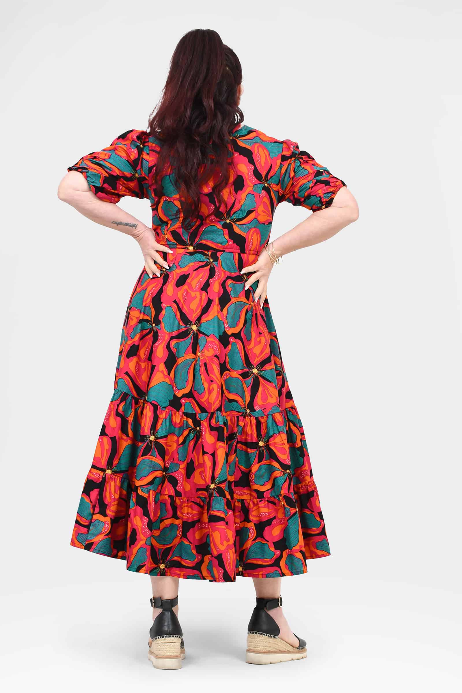 Tiered midi dress in vibrant coral and teal floral print, back view with puff sleeves