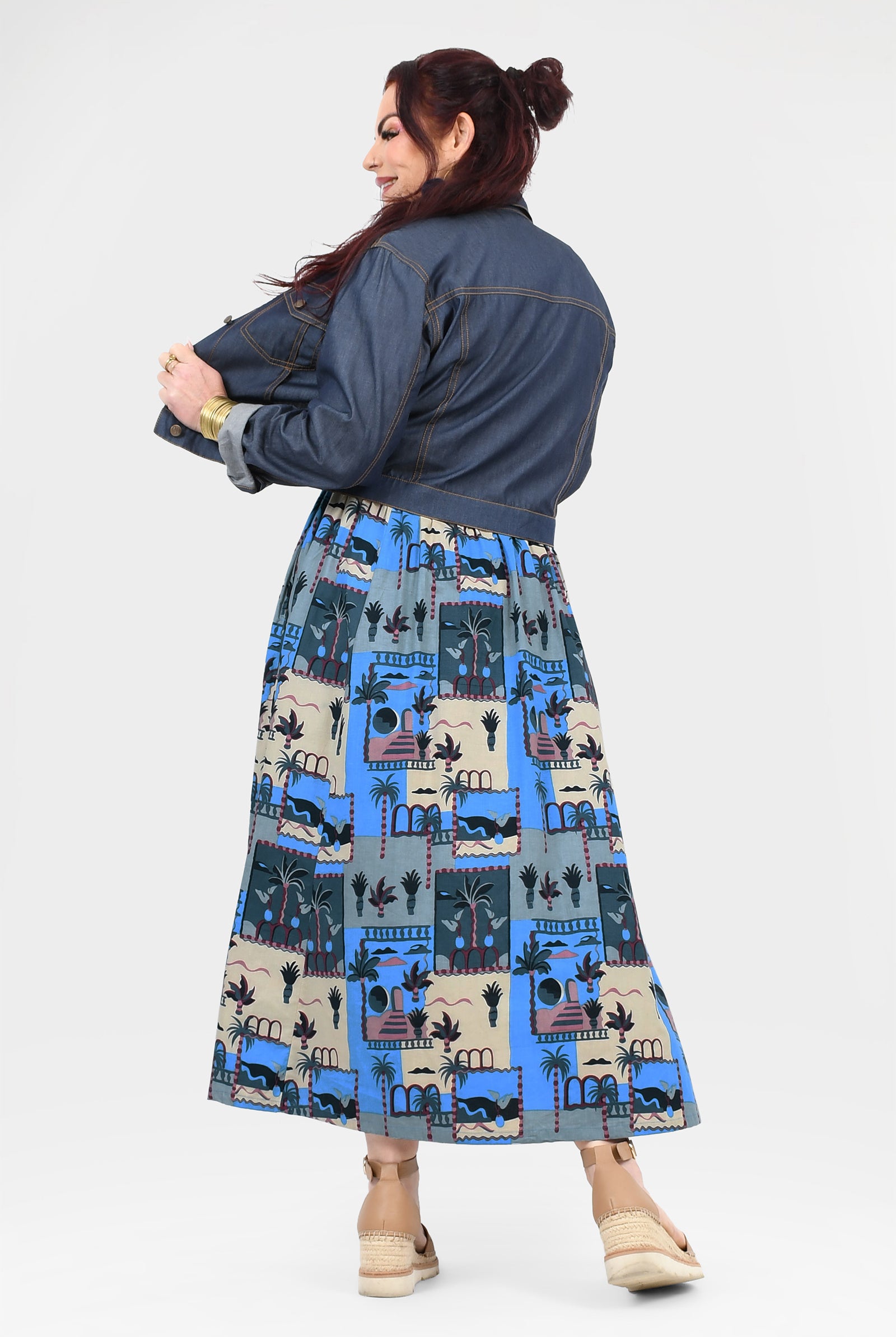 Back view of blue-and-cream illustrated long dress with dark denim jacket and full skirt