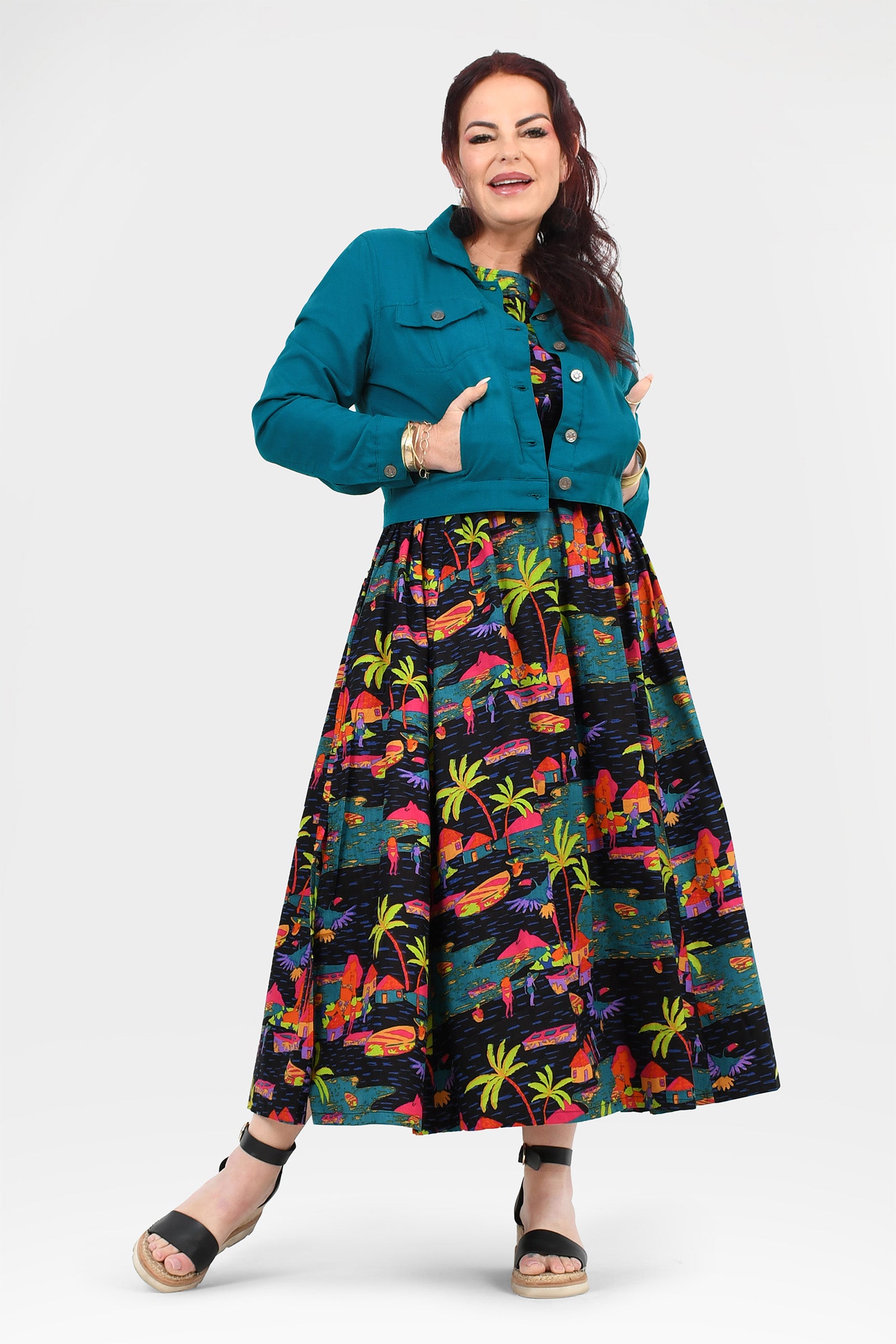 Tropical print long skirt with flared hem peeking under a teal jacket