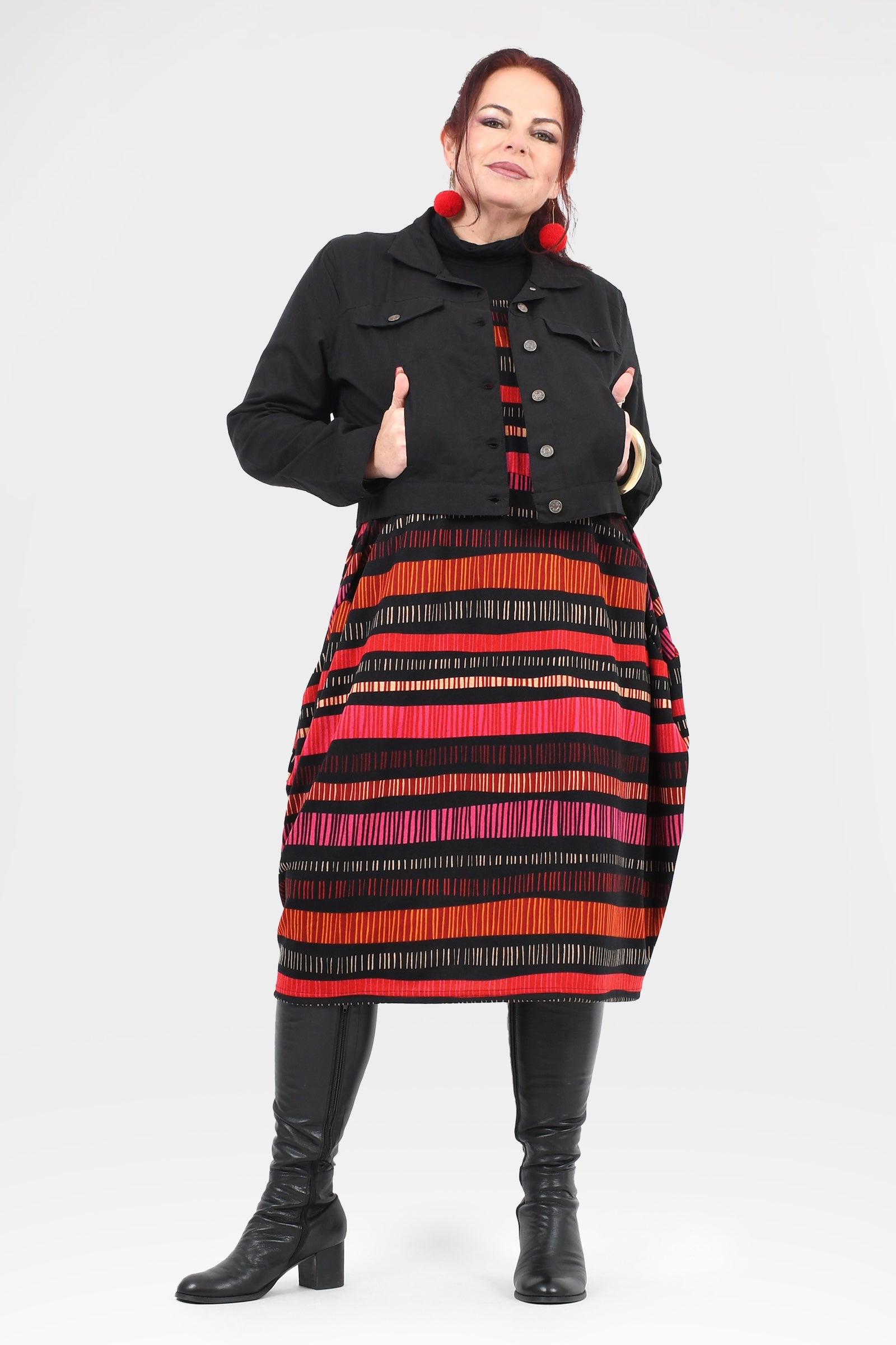 Woman wearing a black jacket and colorful striped skirt on a white background