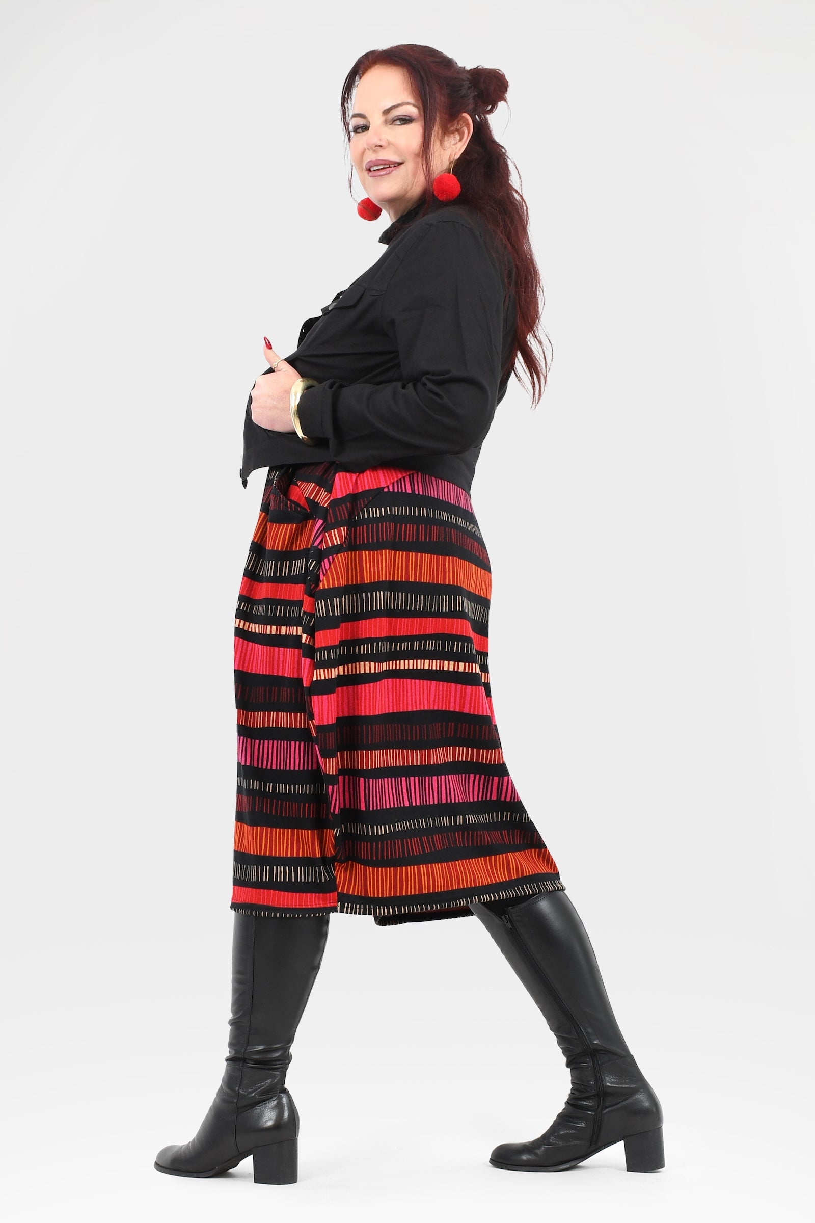 Woman wearing a black top and colorful striped pants on a white background