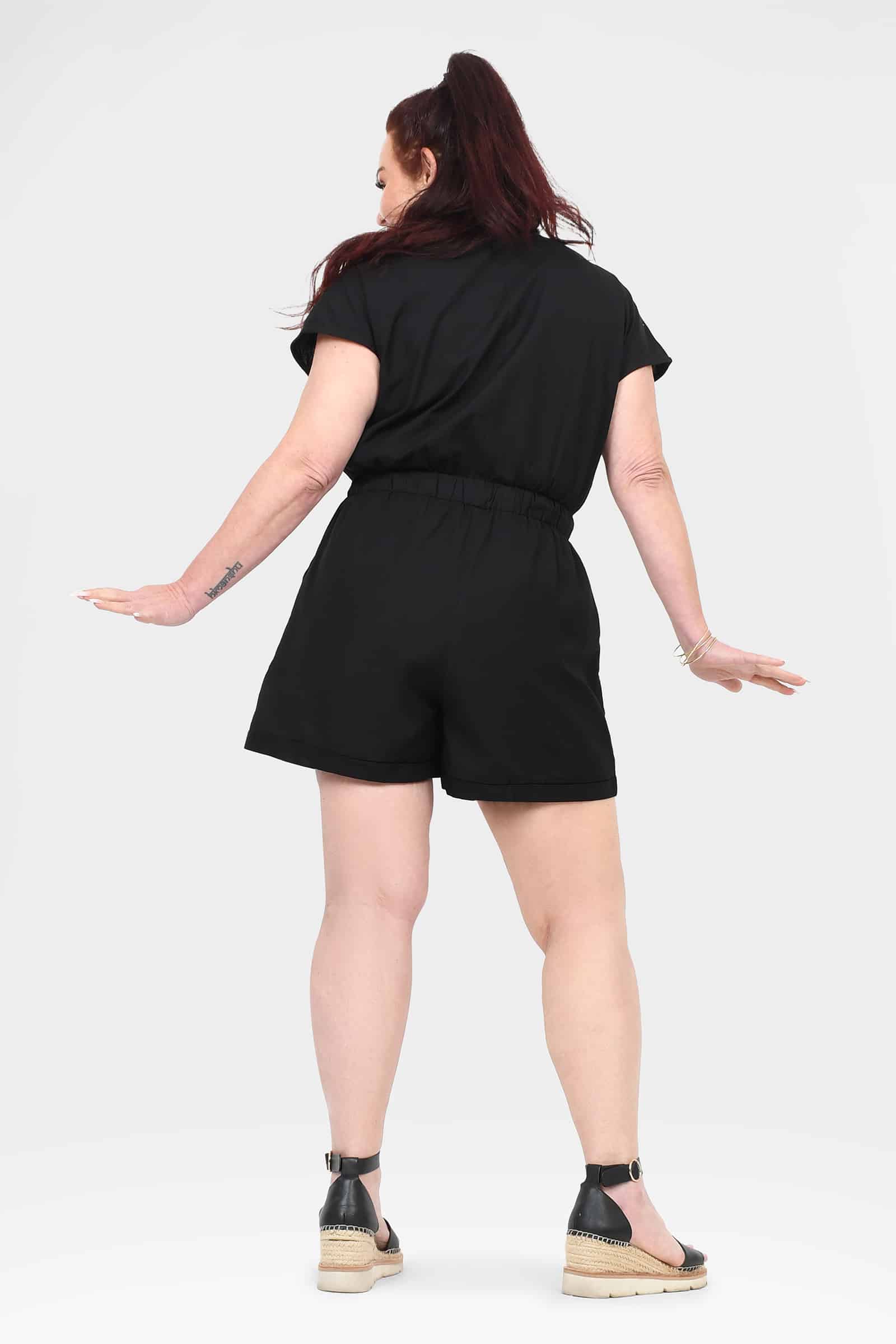 Black short-sleeve romper shown from the back, tie waist with above-knee shorts