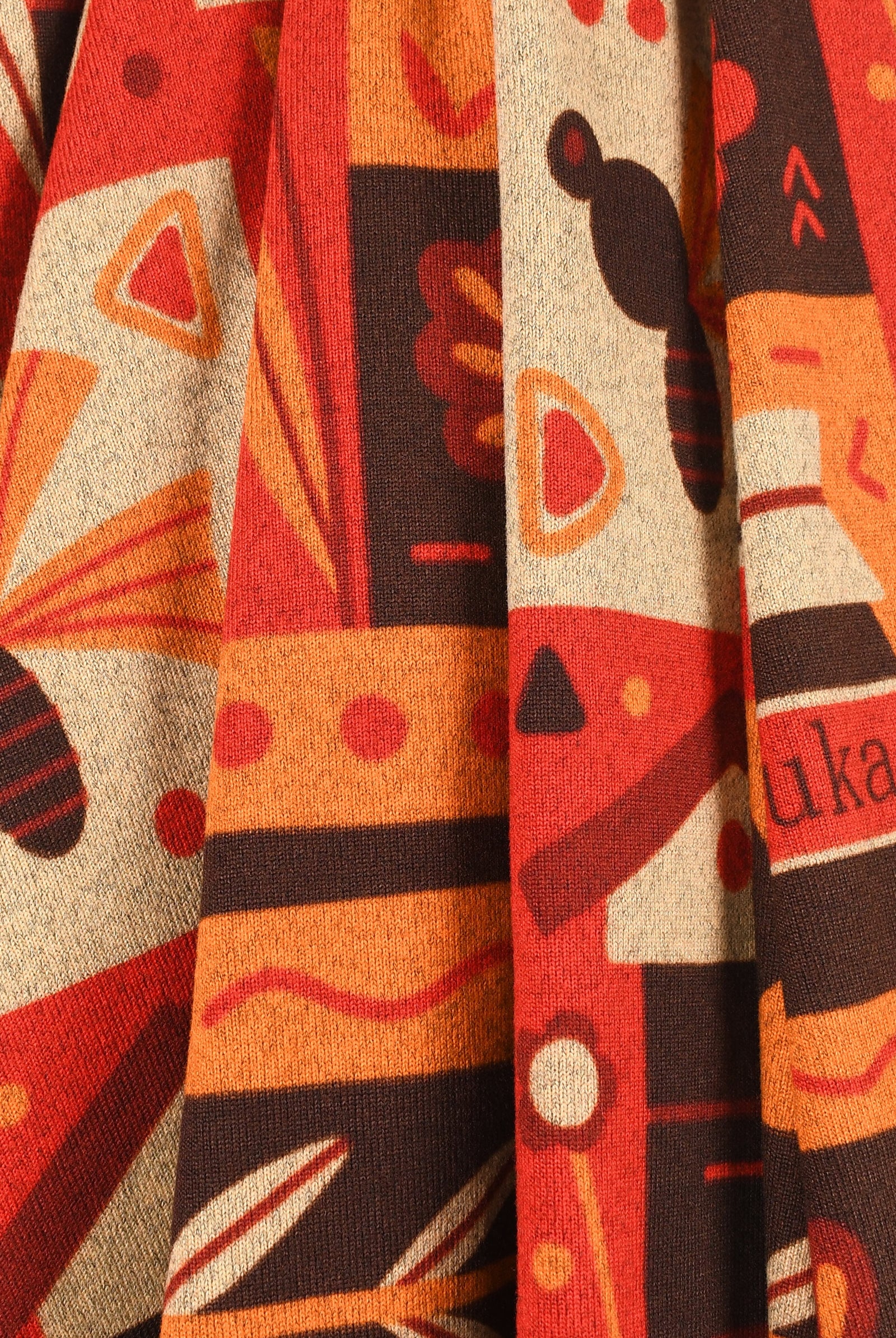 Close-up of a fabric with abstract patterns in red, orange, and black.