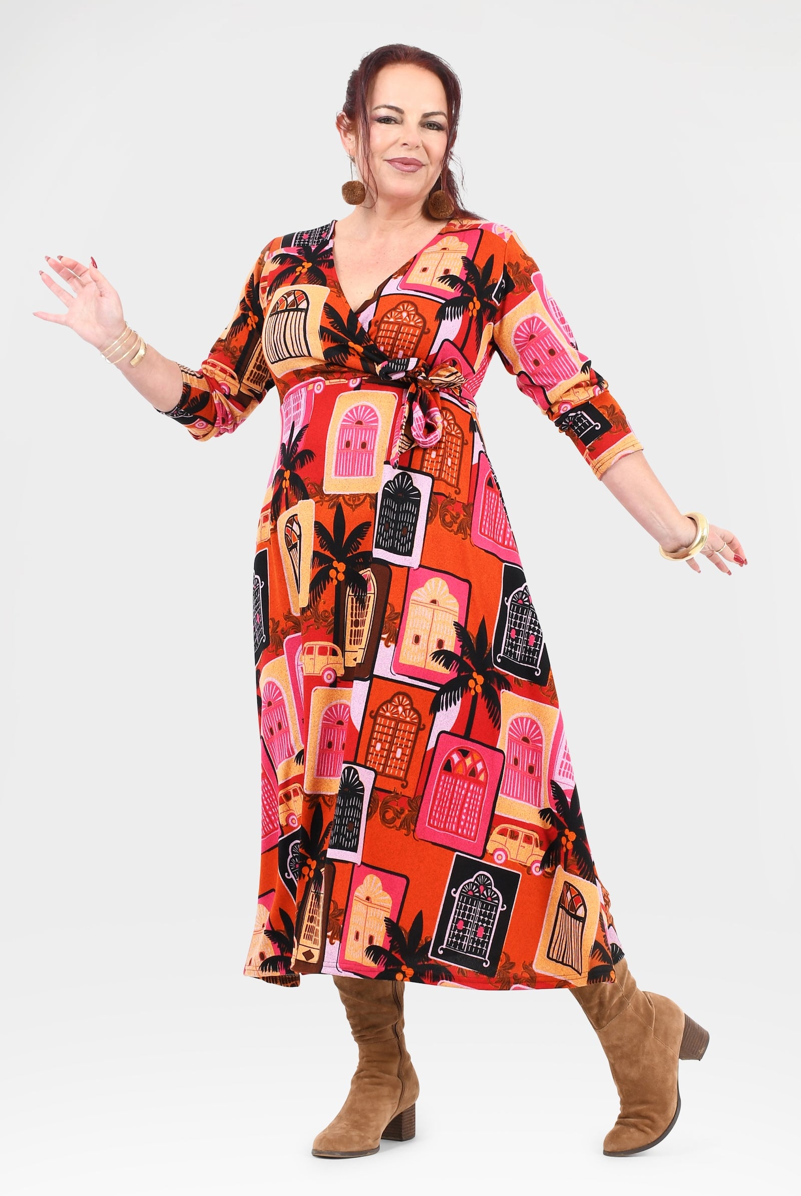 Woman wearing a colorful patterned dress with brown boots on a white background