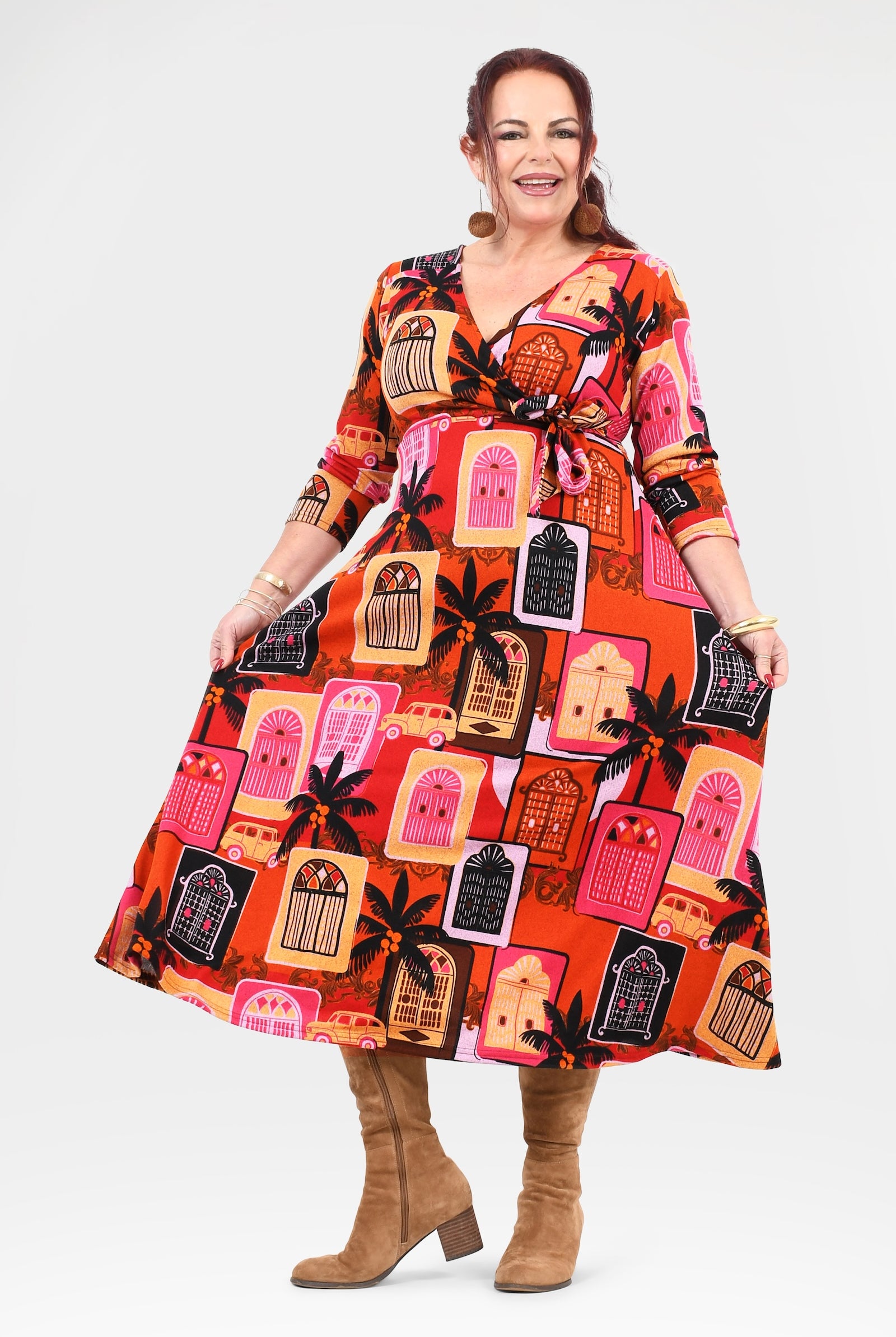 Woman wearing a colorful dress with a pattern of houses and palm trees on a white background