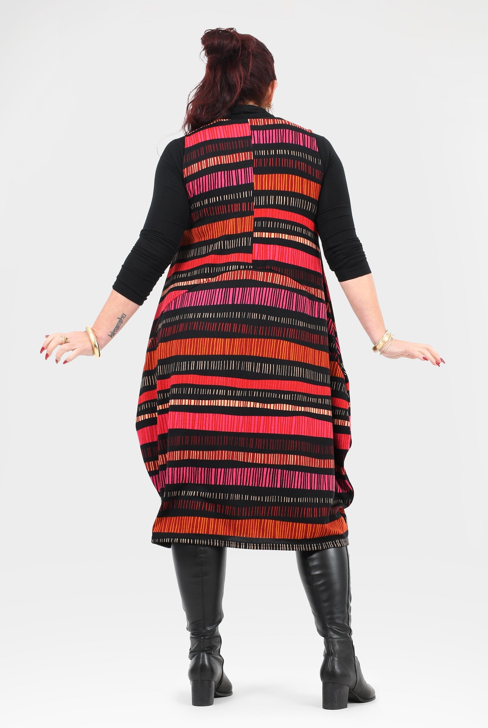 Woman wearing a colorful striped dress with black boots on a white background
