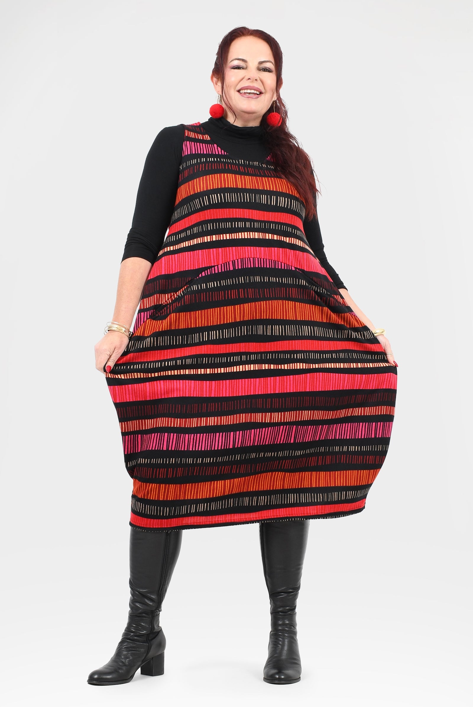 Woman wearing a colorful striped dress with black boots on a white background