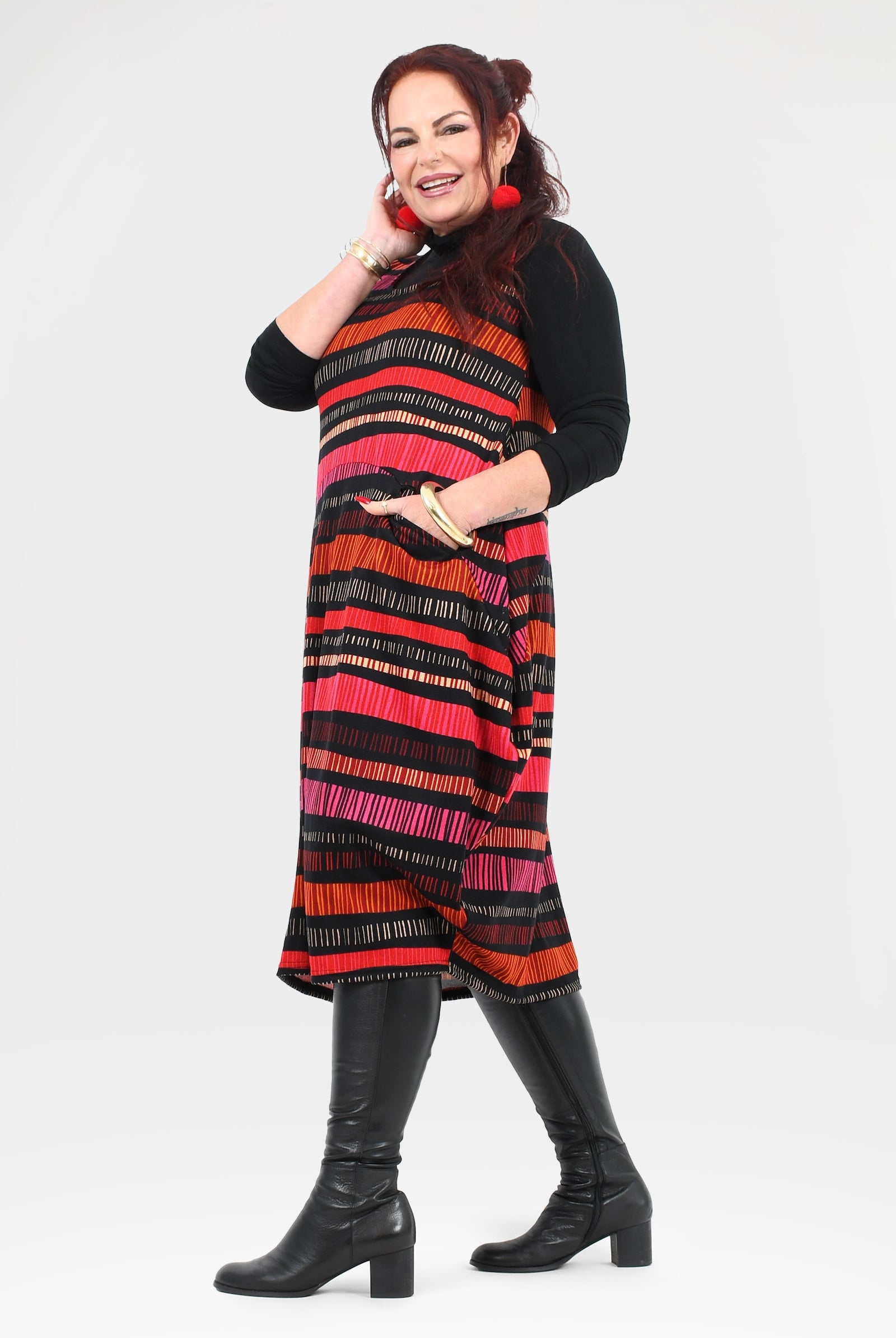 Woman wearing a colorful striped dress with black boots on a white background