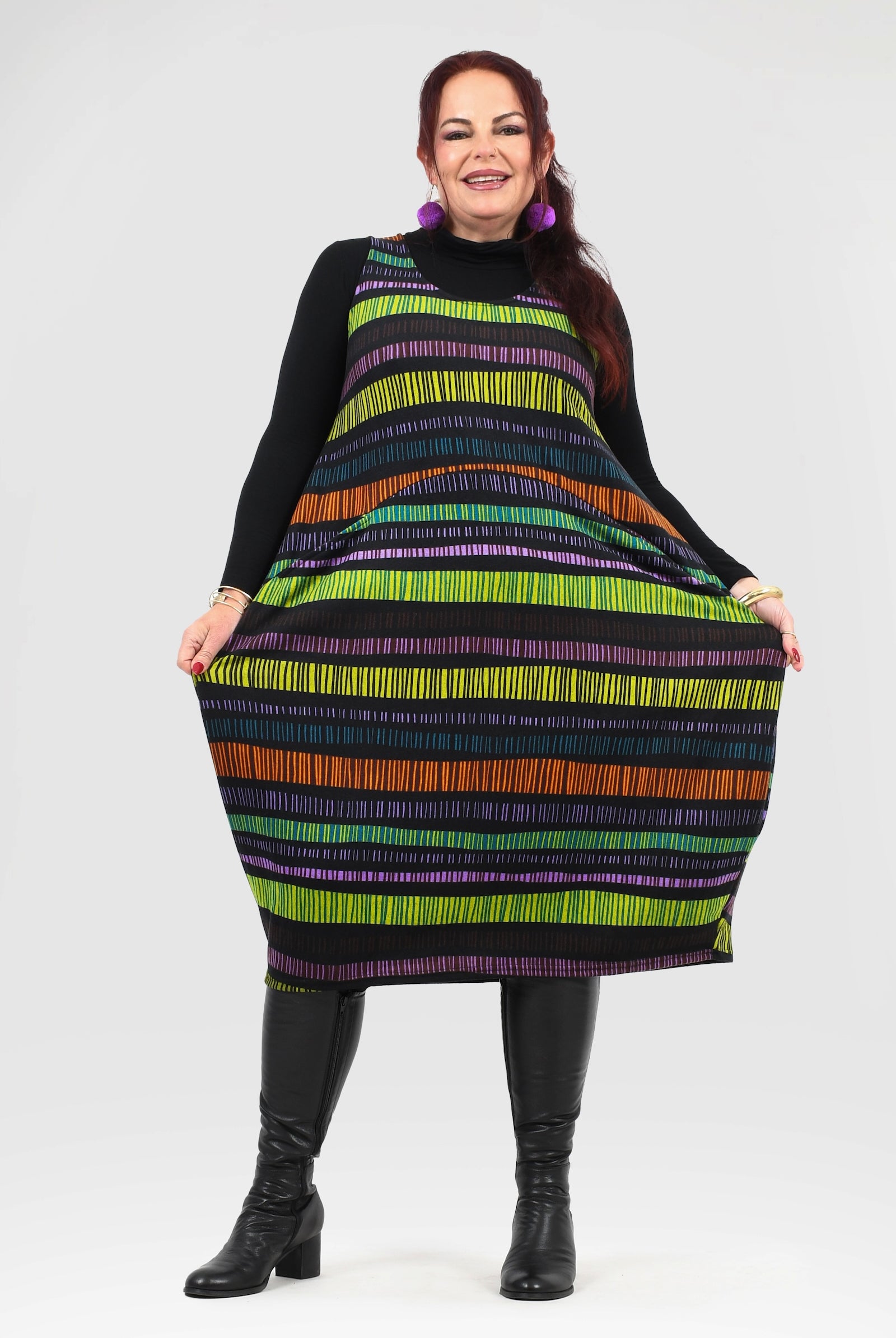 Woman wearing a colorful striped dress with black boots on a white background