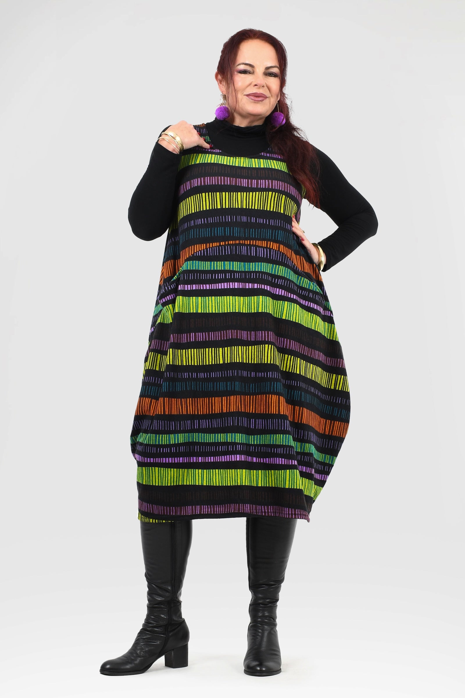 Woman wearing a colorful striped dress with a plain background