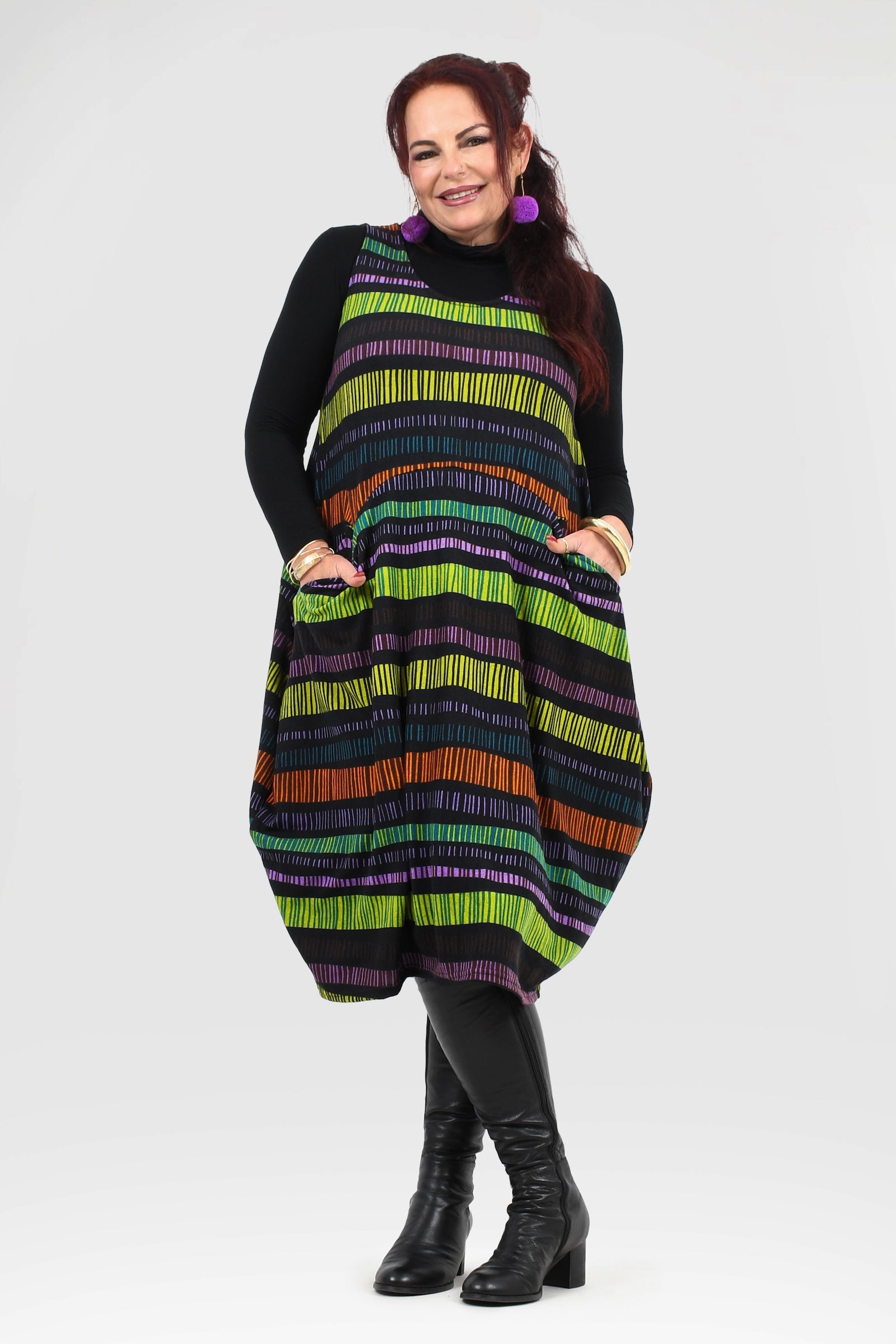 Woman wearing a colorful striped dress with a black turtleneck underneath on a white background