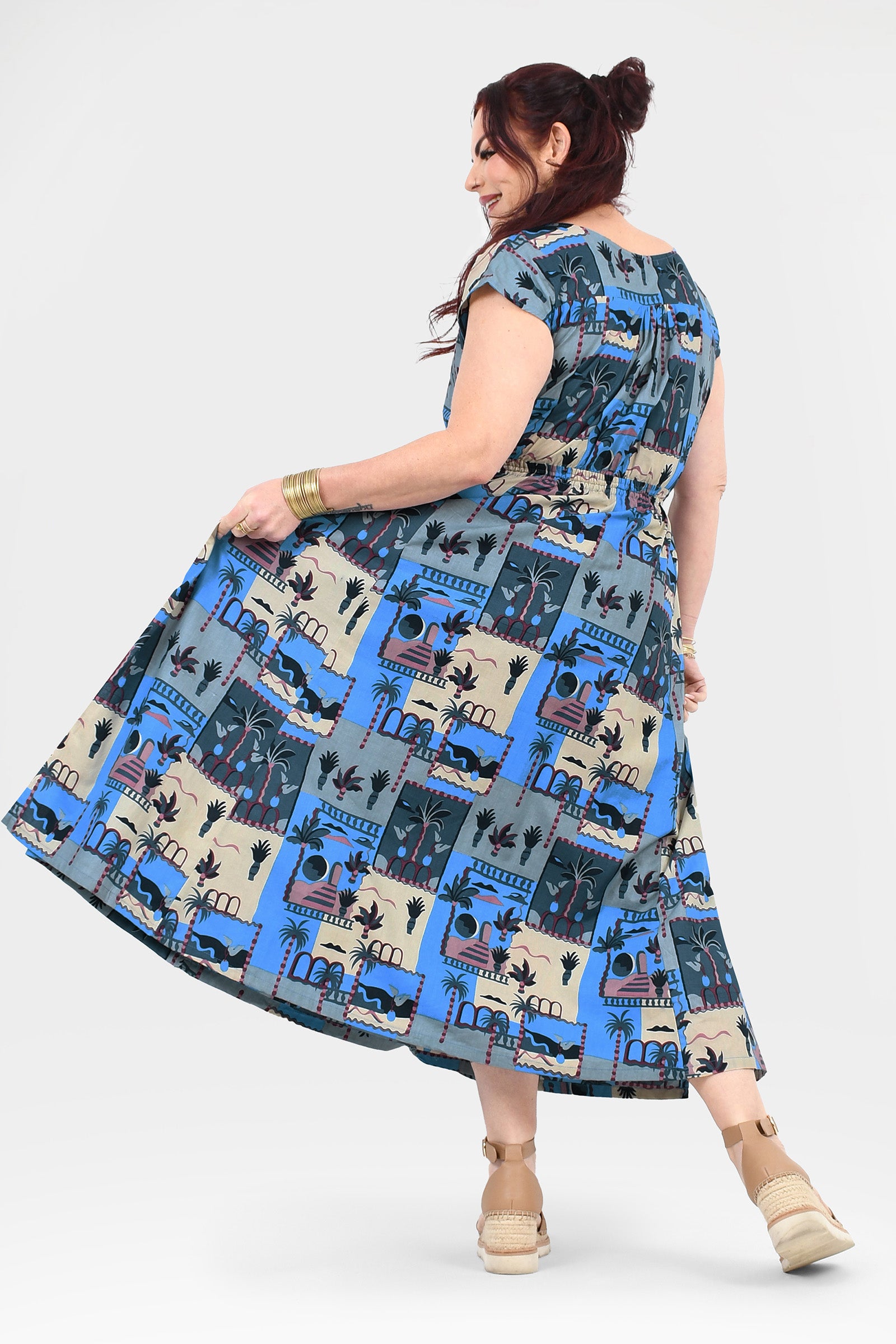 Back view of blue-and-cream cap-sleeve long dress with illustrated skyline print