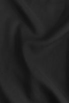 Close-up of black fabric texture with soft drape and gathered seams