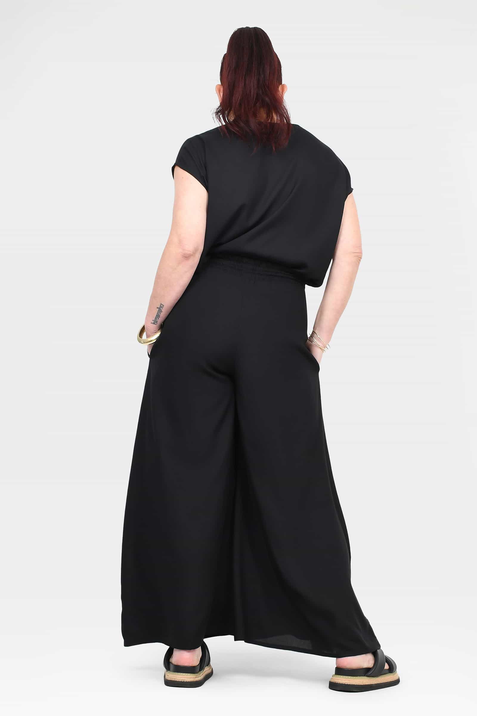 Black wide-leg pants from back view with elastic waist and ankle-length wide legs