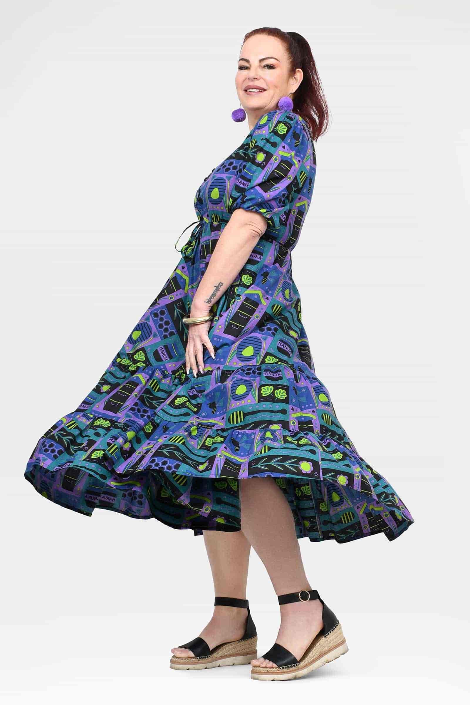 Ava midi dress on model, side view with tiered skirt and teal-purple geometric print