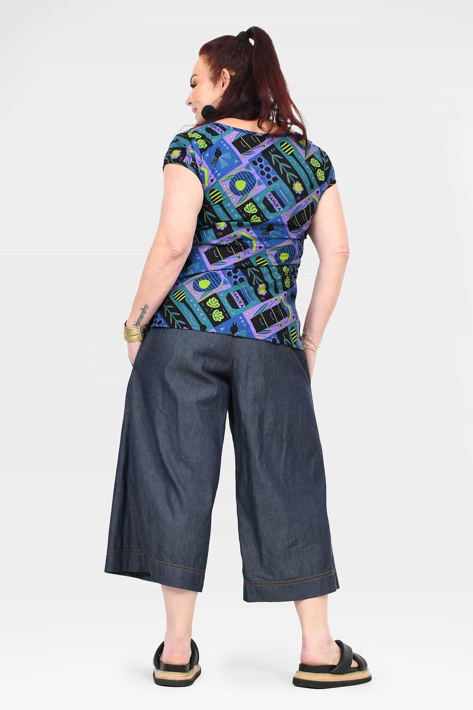 Back view of blue denim 3/4 wide-leg pants with cuffed hem and pockets