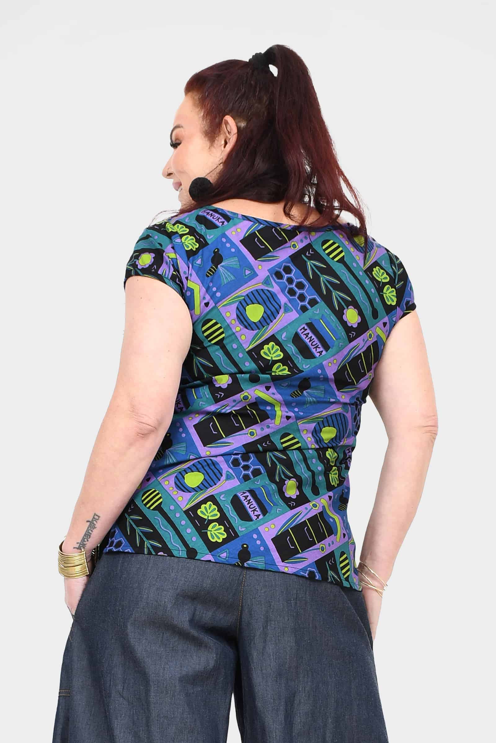 Printed teal back view crew-neck tee with colorful abstract insect-and-gear pattern