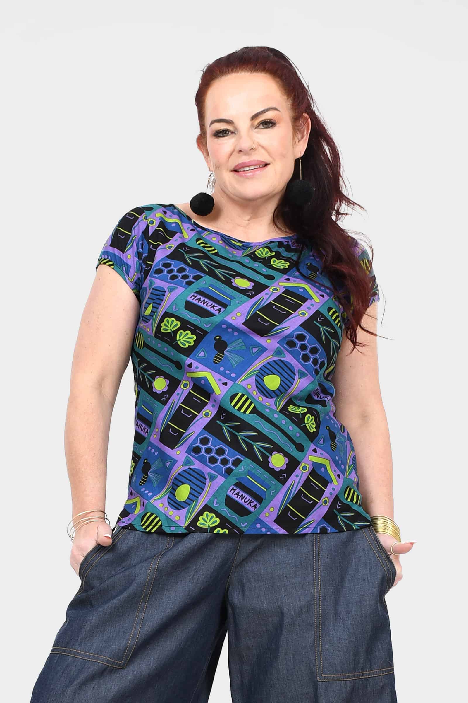 Printed teal crew-neck tee with colorful abstract insect-and-gear pattern, short sleeves