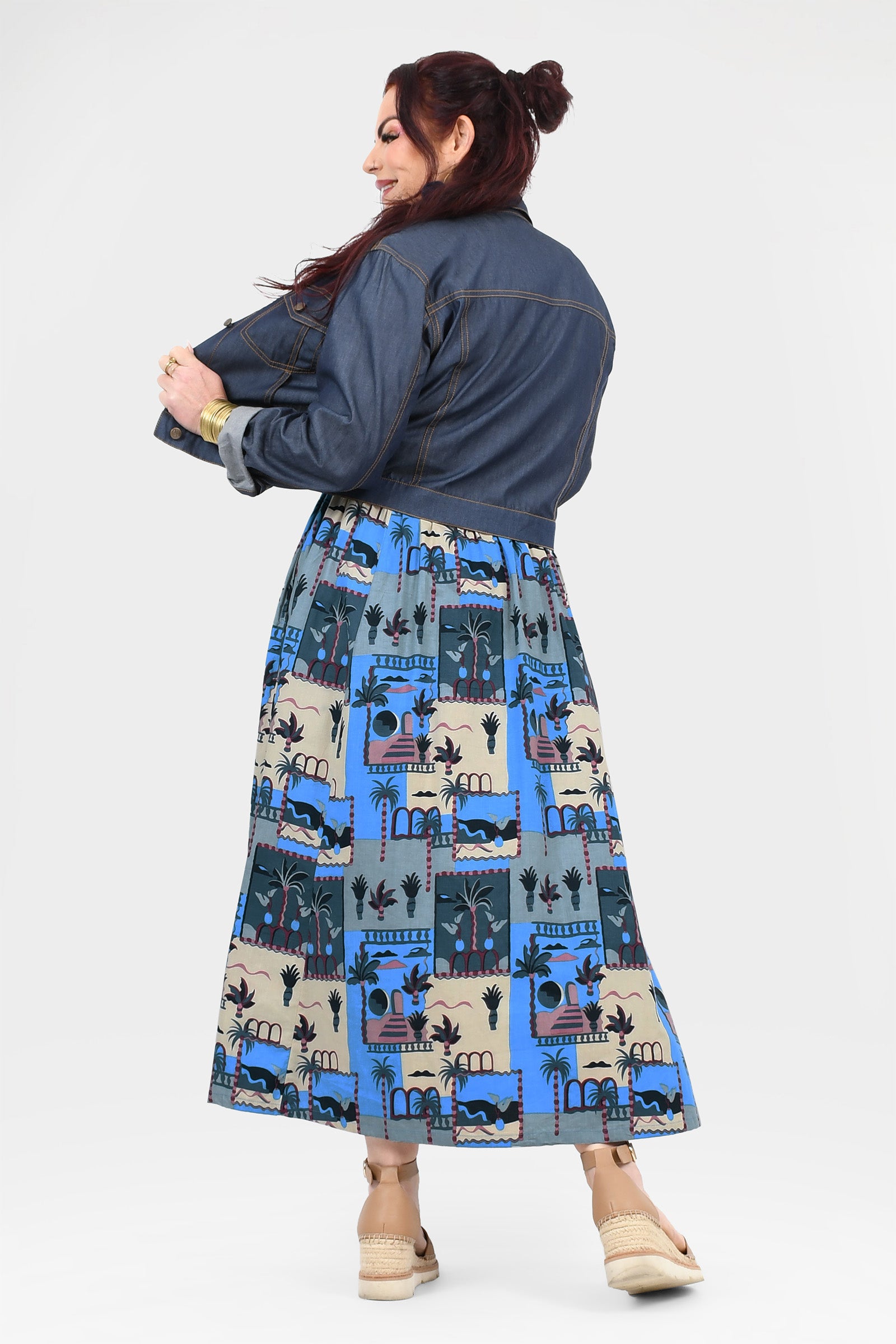 Back view of blue-and-cream illustrated long dress with dark denim jacket and full skirt