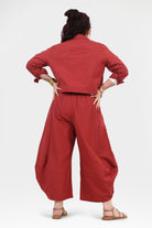 Back view of dark red wide-leg pants with elastic waistband and draped legs.