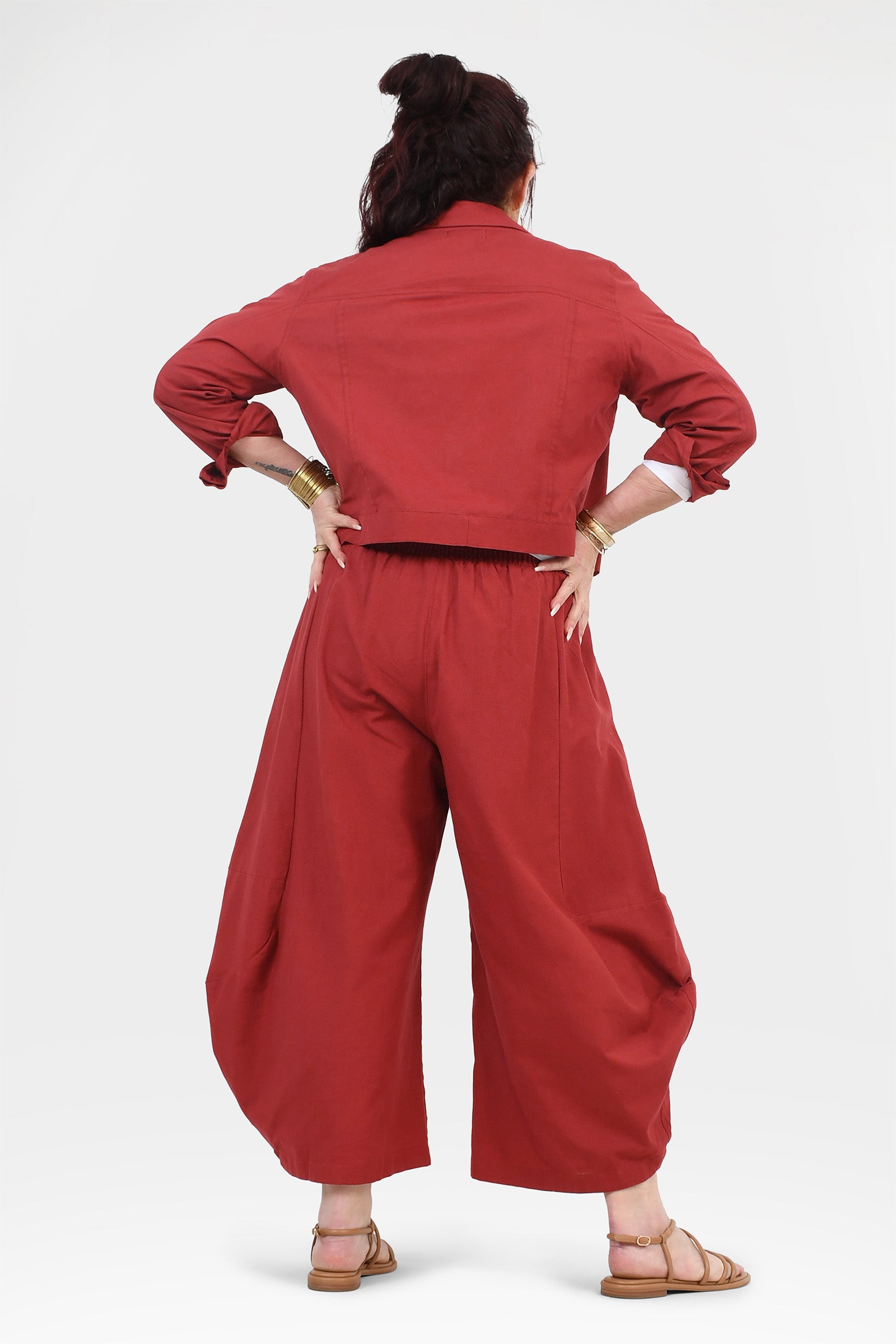 Back view of dark red wide-leg pants with elastic waistband and draped legs.