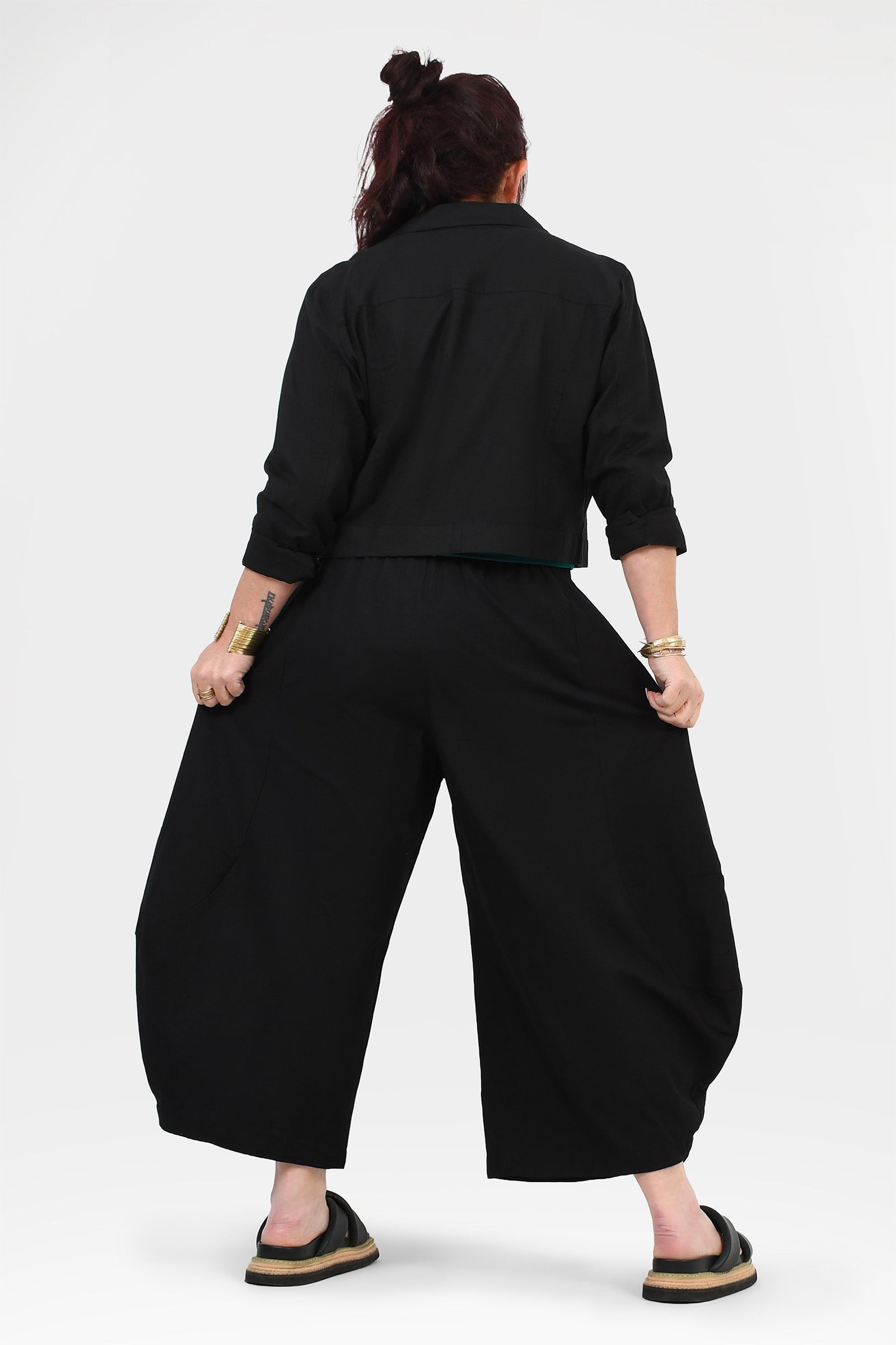 Black wide-leg pants from the back with gathered waist and loose, flowing legs