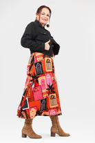 Woman wearing a black jacket and colorful skirt with geometric pattern on a white background