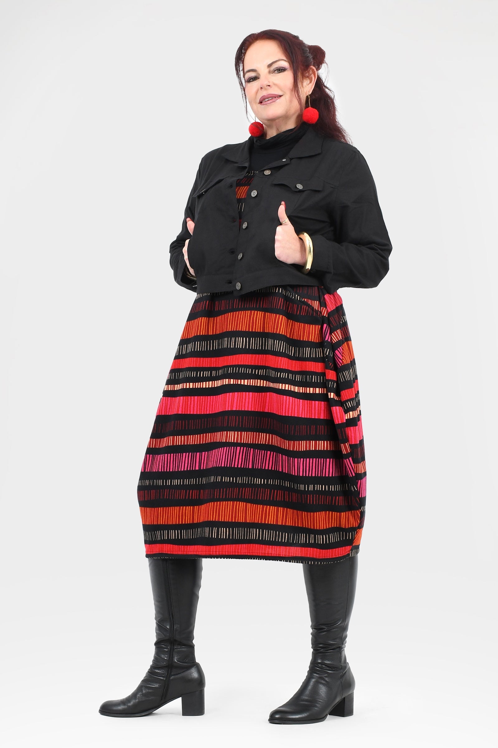Woman wearing a black jacket and colorful striped skirt on a white background