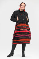 Woman wearing a black jacket and red striped skirt on a white background