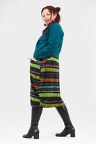 Woman wearing a colorful striped skirt with a teal top on a white background