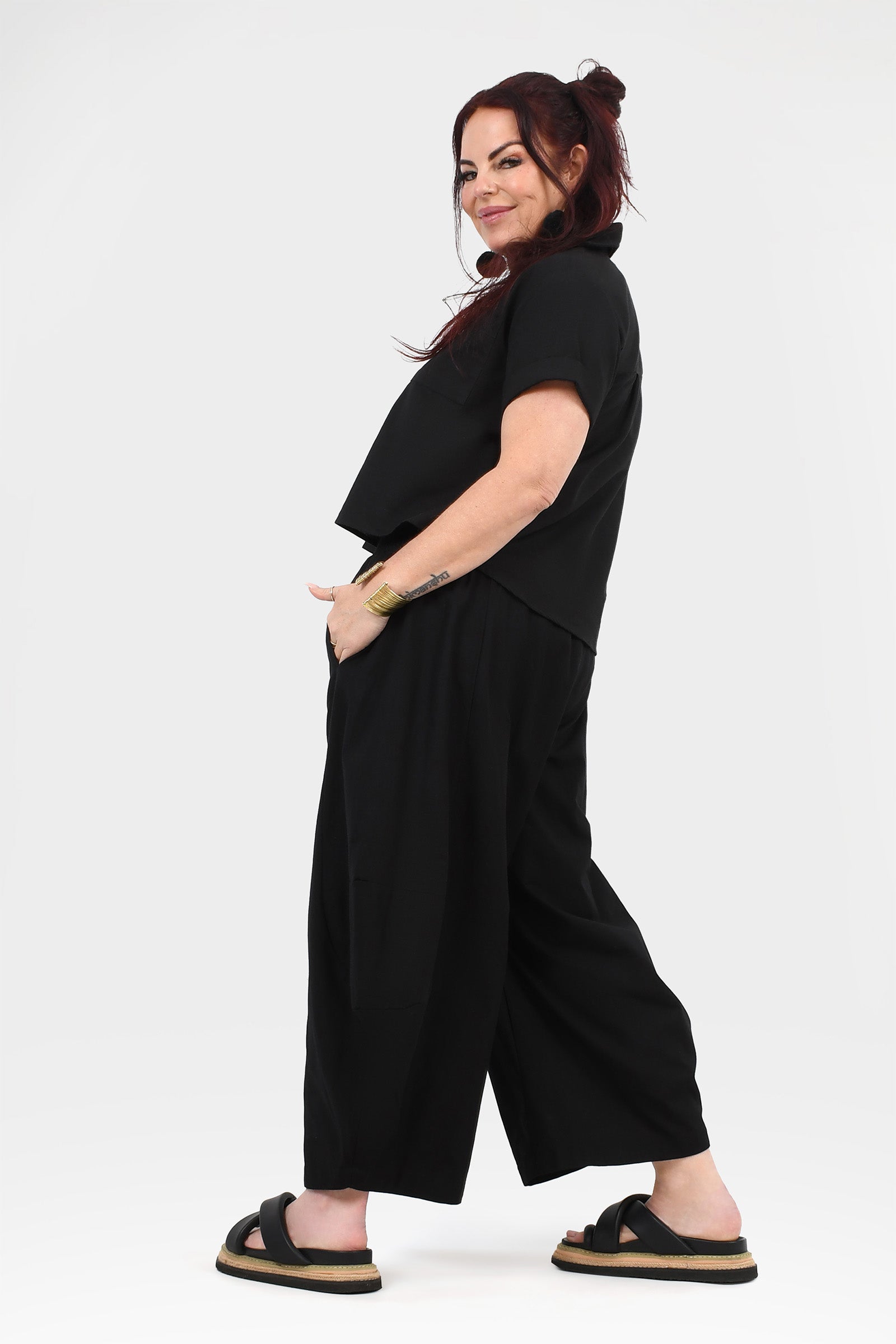 Black wide-leg pants with elastic waistband, side profile and wide cropped hem