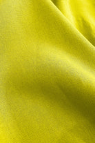 Lime green woven pants fabric close-up with fine textured weave