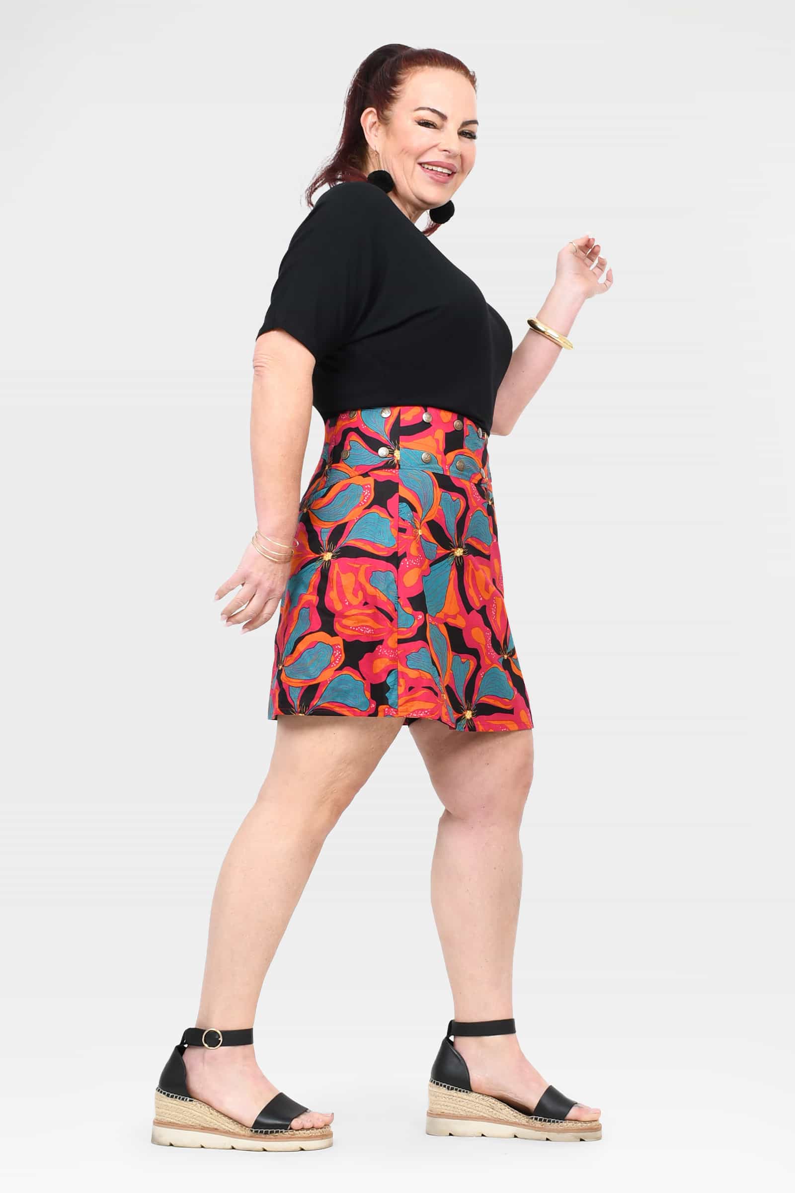 Above-knee A-line short skirt with black waistband and bright tropical print, side view