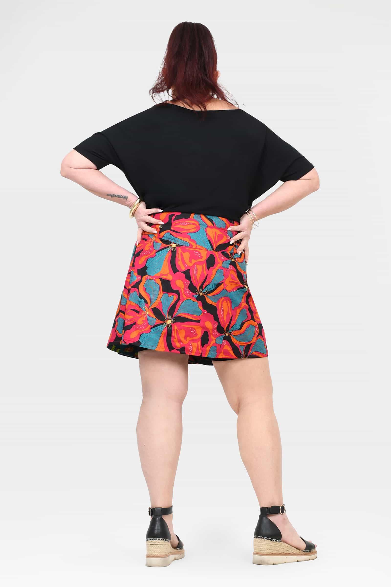 Above-knee A-line short skirt with black waistband and bright tropical print, back view