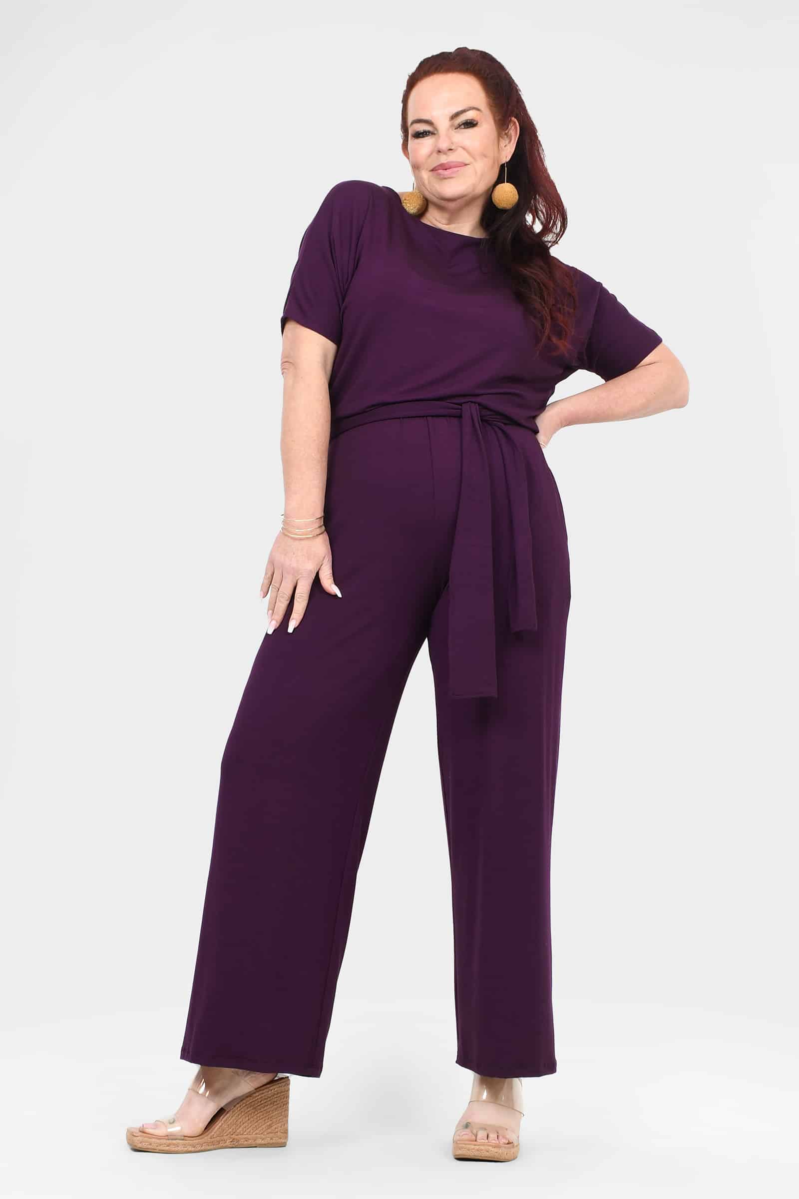 Women's aubergine jumpsuit front view with crew neck, tie waist belt, wide-leg pants