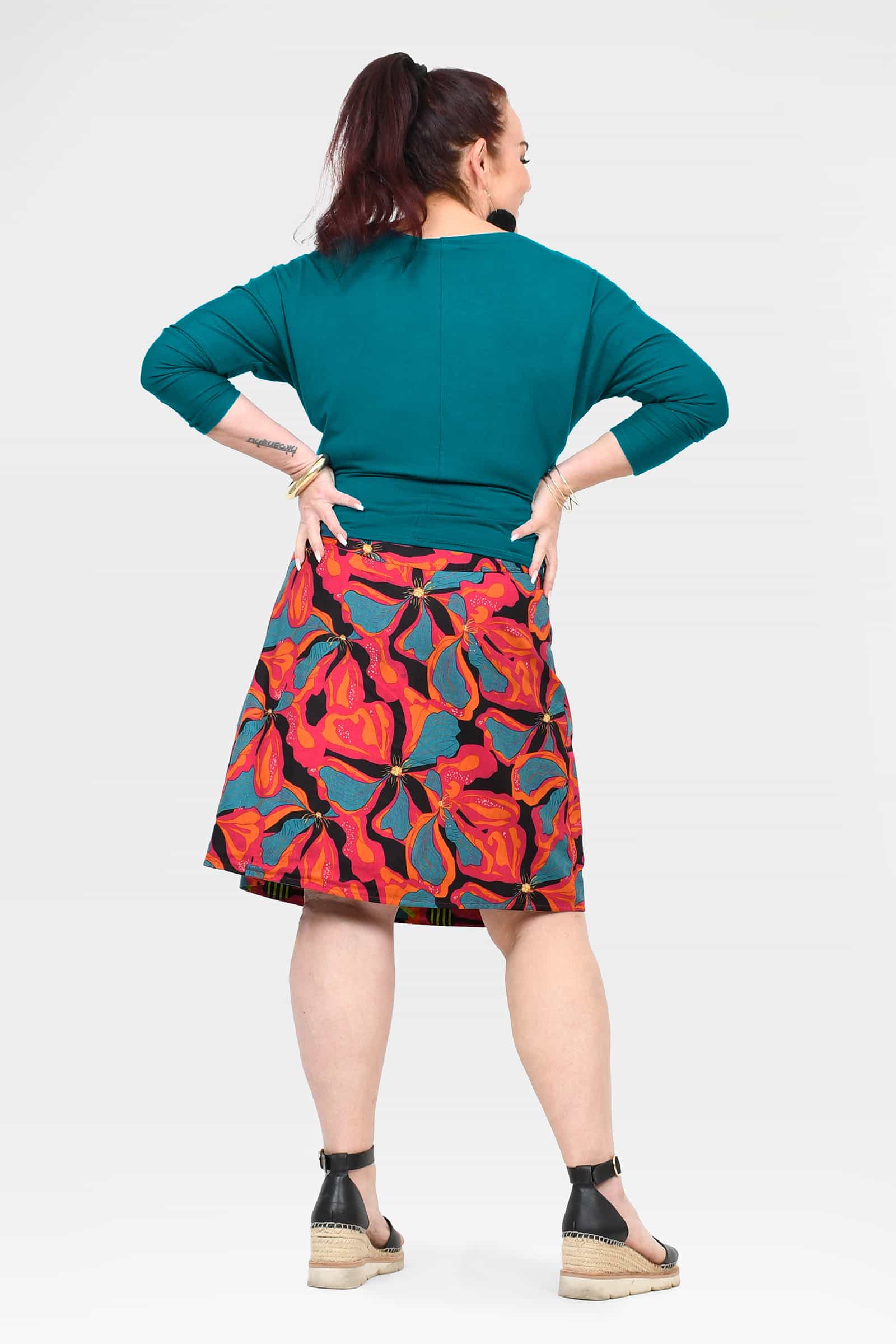 Long reversible button skirt back view; teal rear panel with colorful print