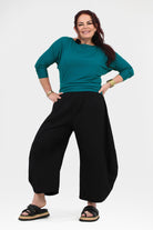 Black wide-leg pants with elastic waistband, relaxed drape and ankle-length hem