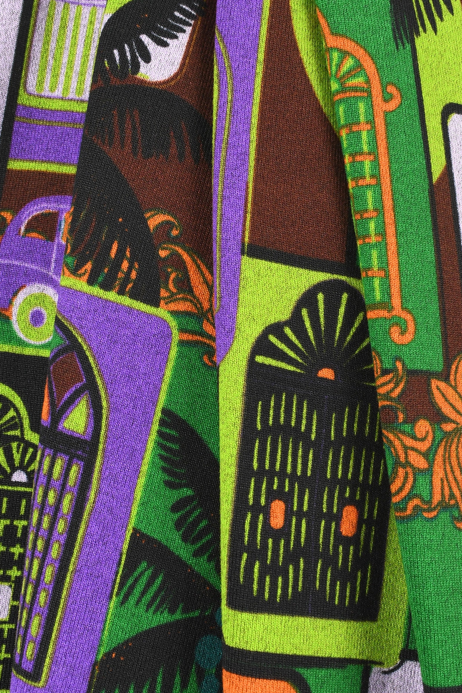 Colorful fabric with abstract patterns in green, purple, black, and orange.