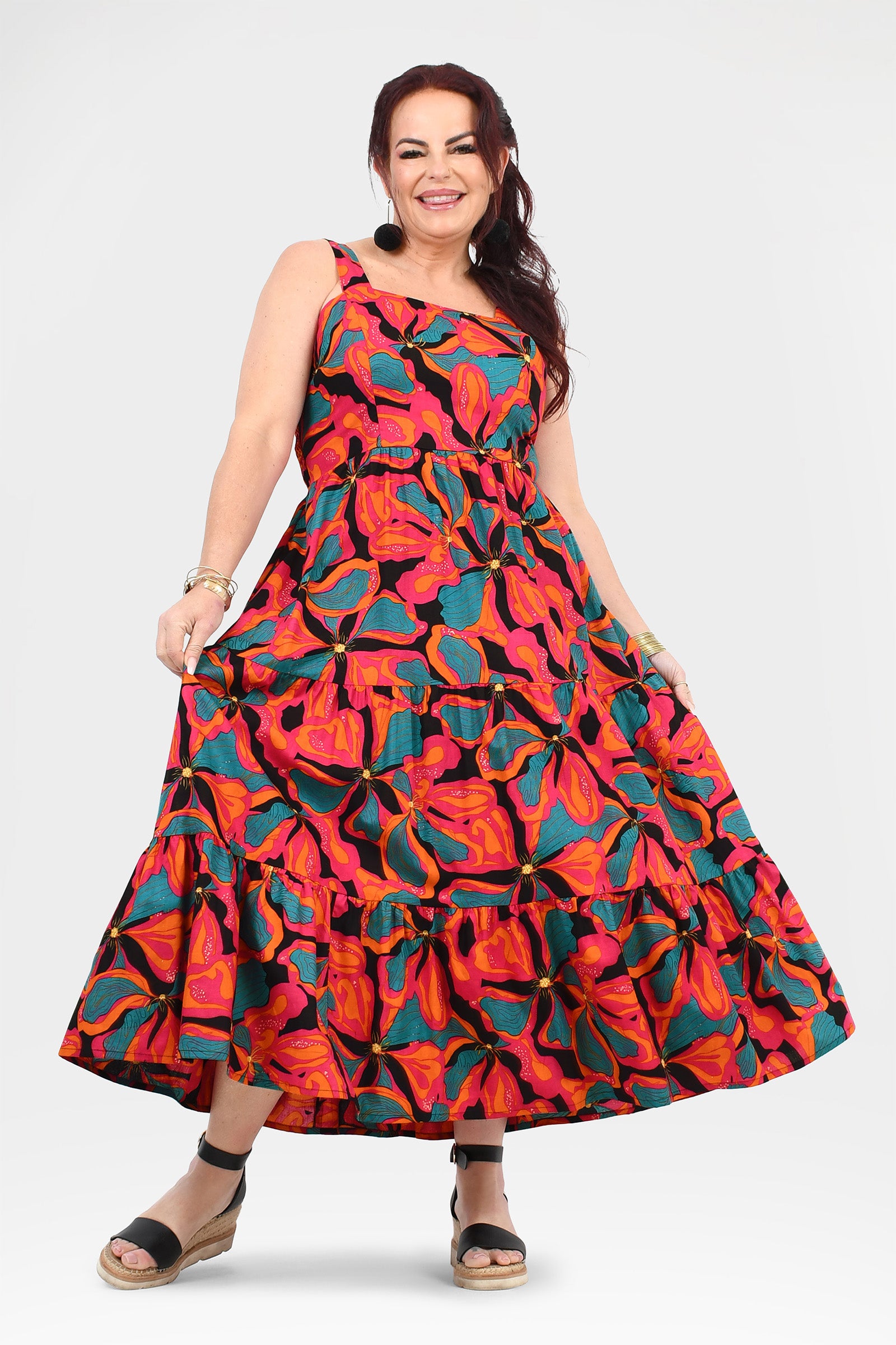 Sleeveless maxi dress featuring tiered ruffles and abstract floral pattern in red, pink, and teal