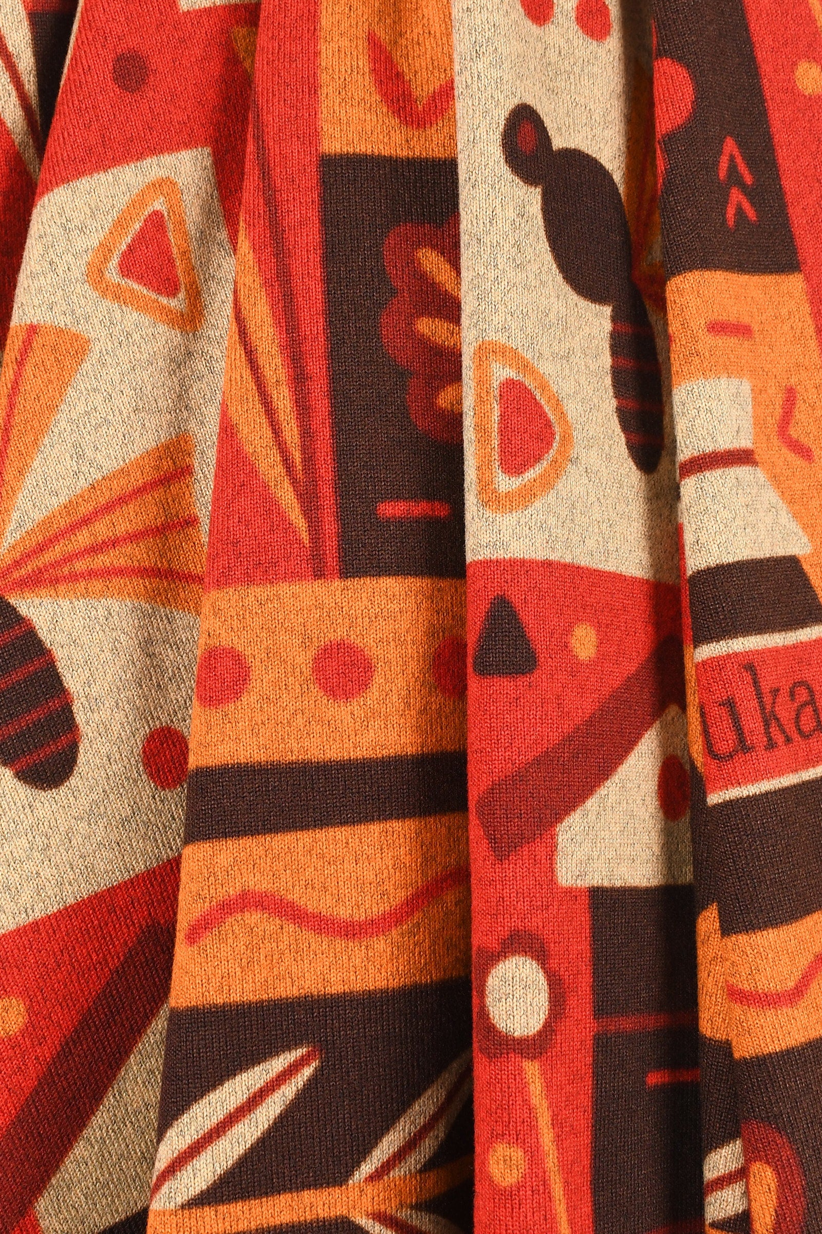 Close-up of a fabric with abstract patterns in red, orange, and black.