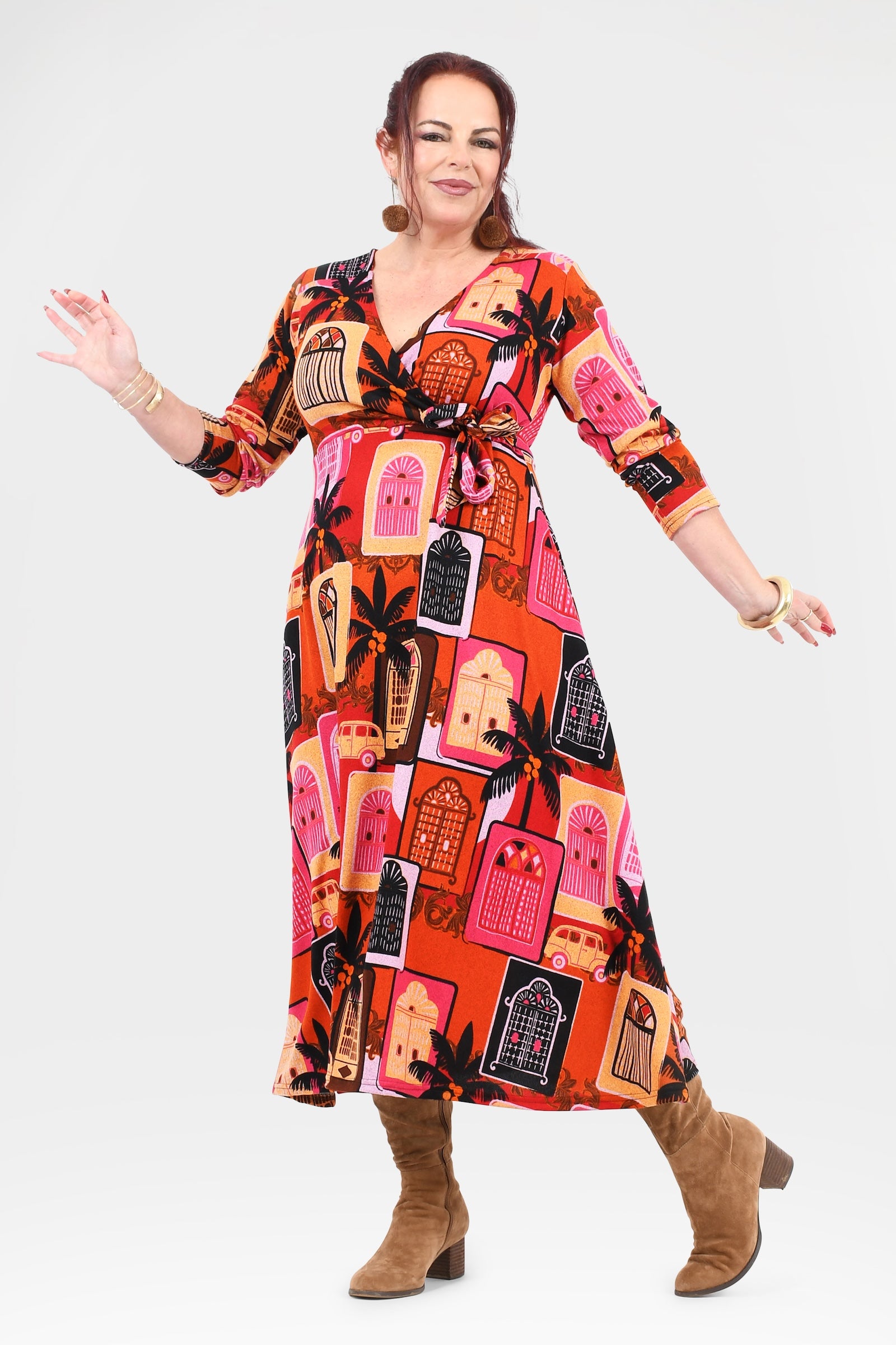 Woman wearing a colorful patterned dress with brown boots on a white background