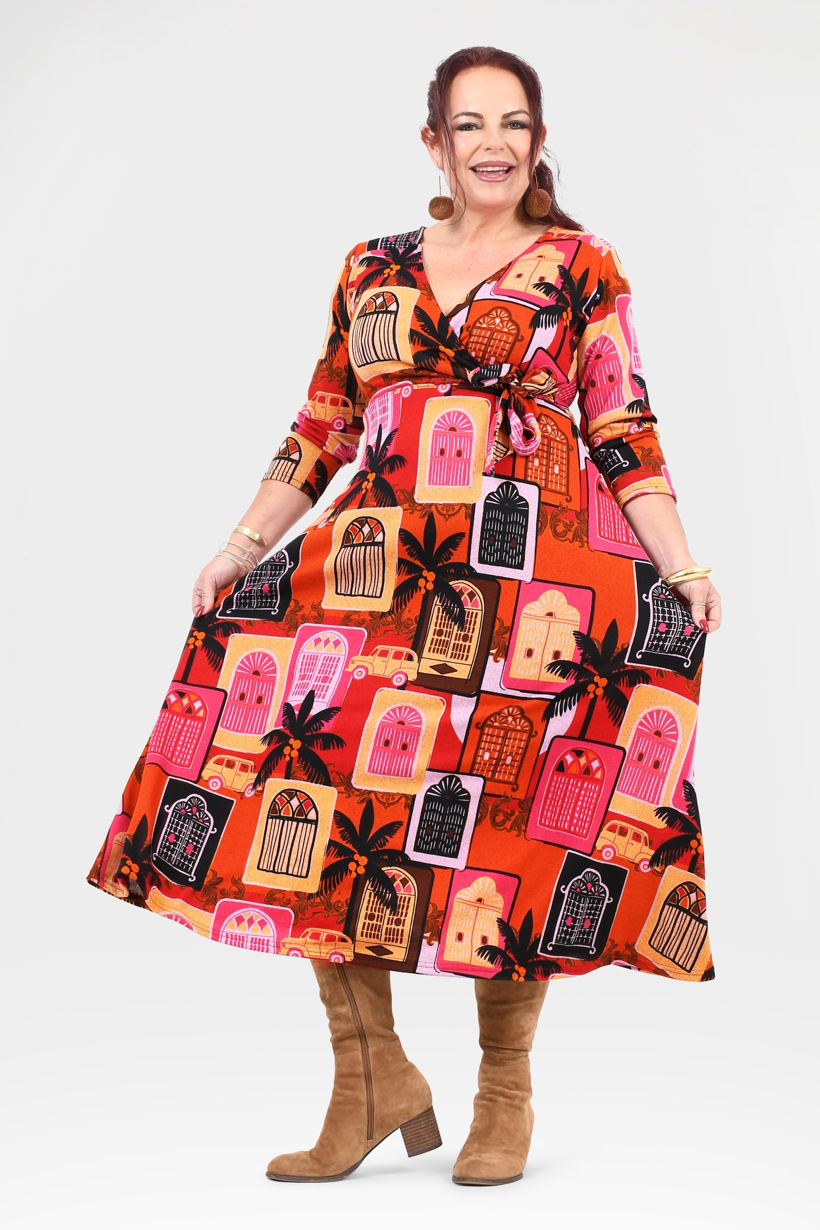 Woman wearing a colorful dress with a pattern of houses and palm trees on a white background