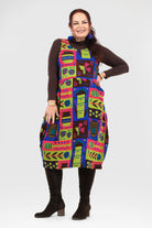 Woman wearing a colorful patterned dress with a plain background