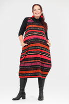 Woman wearing a black, red, and orange striped dress on a white background