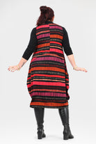 Woman wearing a colorful striped dress with black boots on a white background