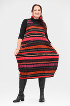 Woman wearing a colorful striped dress with black boots on a white background