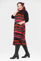 Woman wearing a colorful striped dress with black boots on a white background