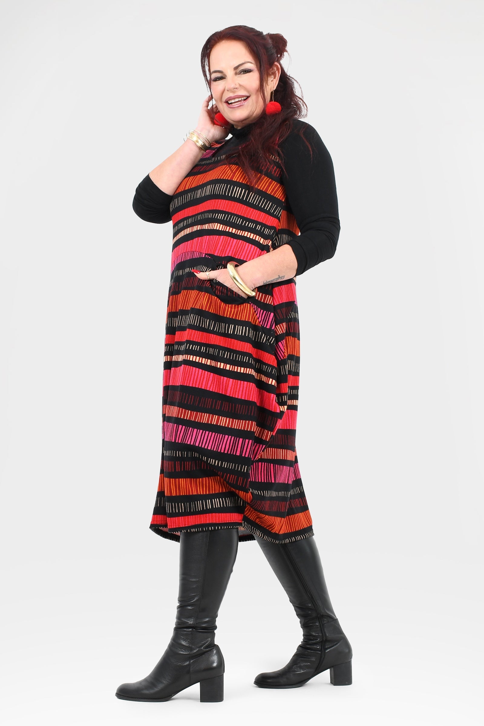 Woman wearing a colorful striped dress with black boots on a white background