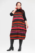 Woman wearing a colorful striped dress with a black turtleneck and black boots on a white background