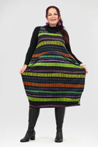 Woman wearing a colorful striped dress with black boots on a white background